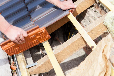 Man inserting tiles on roof