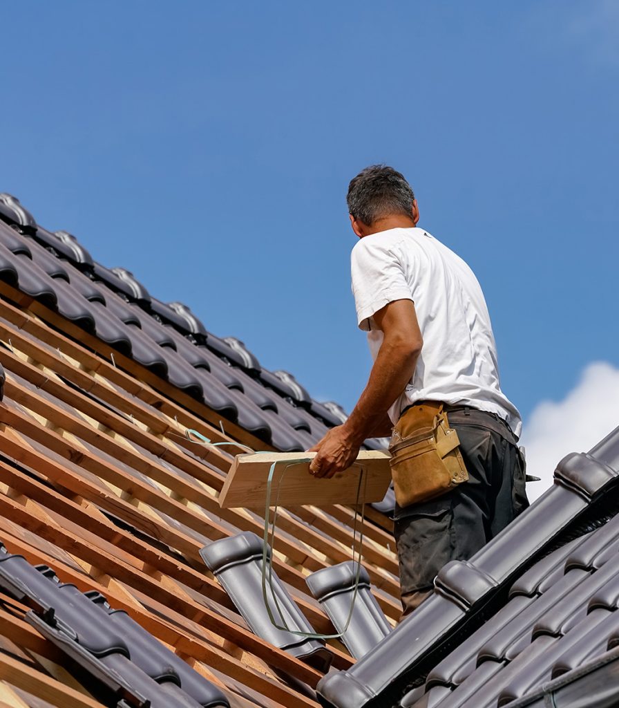 man standing on roof, holding tiles